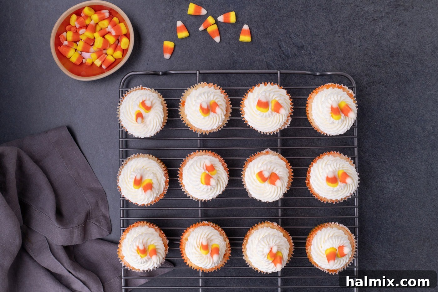 Spooky Sweet Candy Corn Cheesecake Minis 13 Whipped cream and candy corn decorating the tops of candy corn cheesecakes on a wire cooling rack.