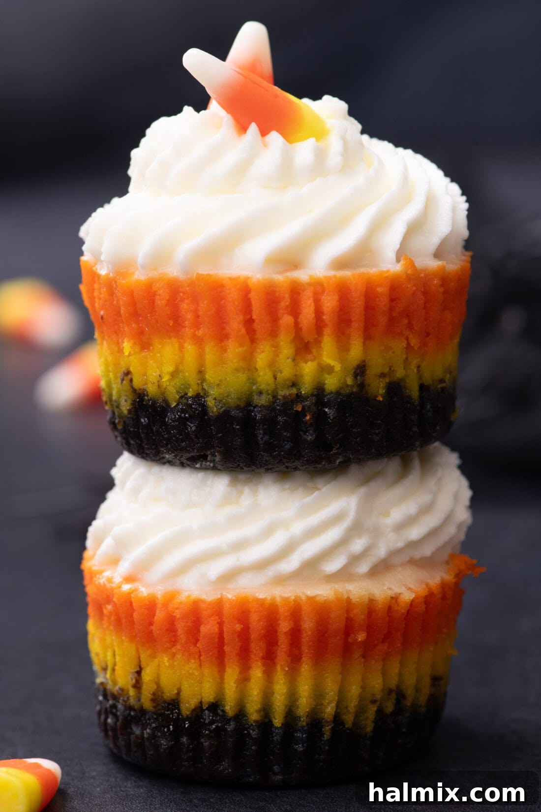 Spooky Sweet Candy Corn Cheesecake Minis 3 Two Mini Candy Corn Cheesecakes stacked on top of each other, highlighting the distinct colorful layers.