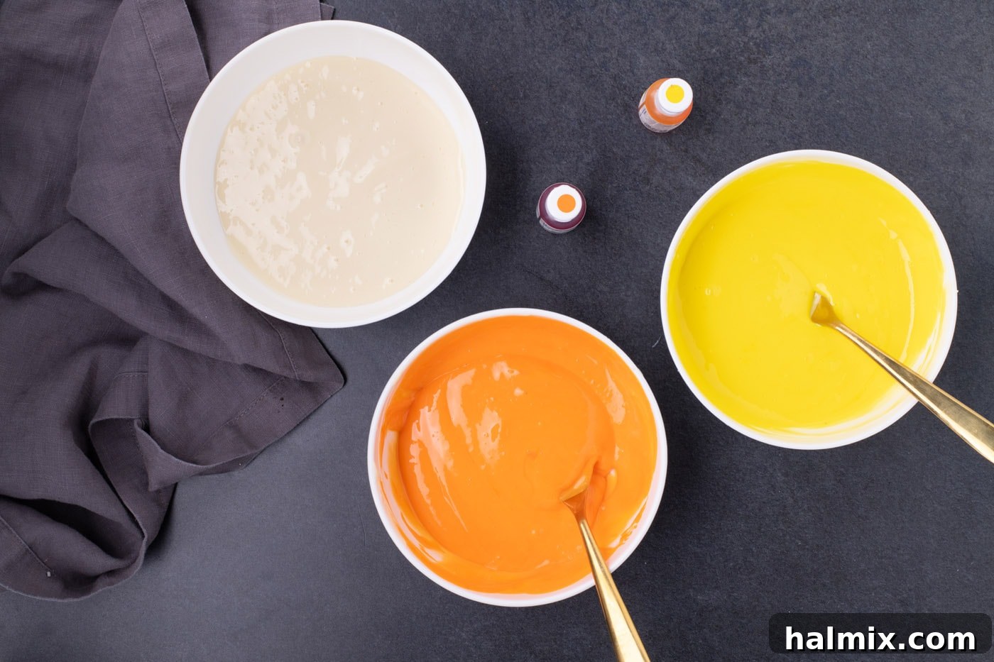 Spooky Sweet Candy Corn Cheesecake Minis 7 Three bowls of cheesecake filling: yellow, orange, and cream-colored, ready for layering.