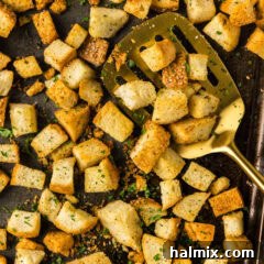 Close up photo of a spatula on a baking sheet of Homemade Croutons