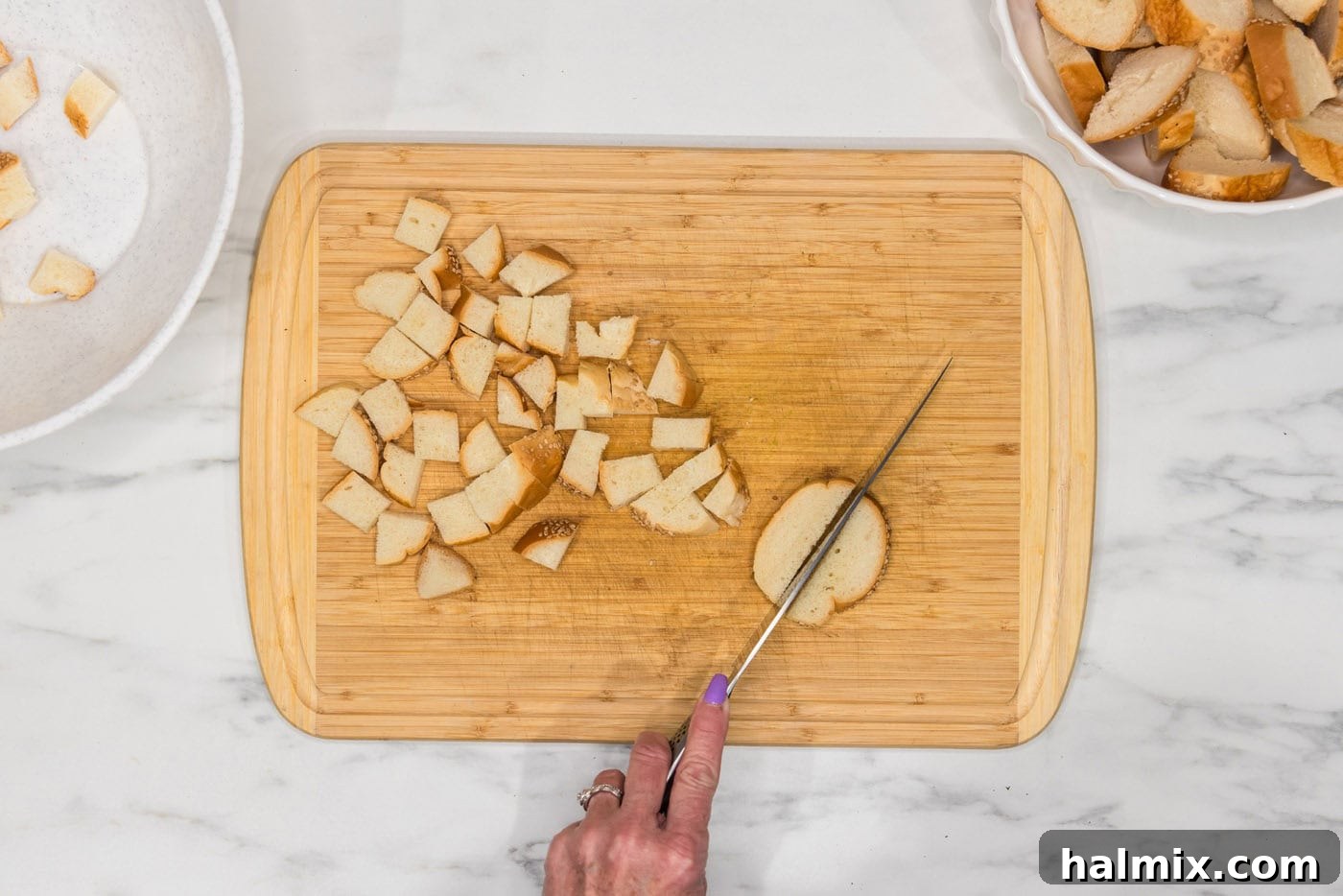 slicing breads into cubes on a cutting board