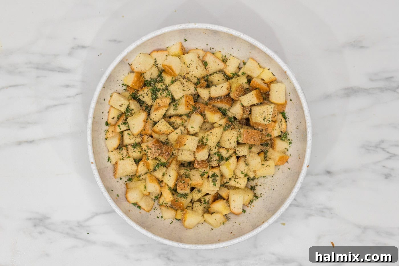cubed bread with seasonings and herbs in a large bowl
