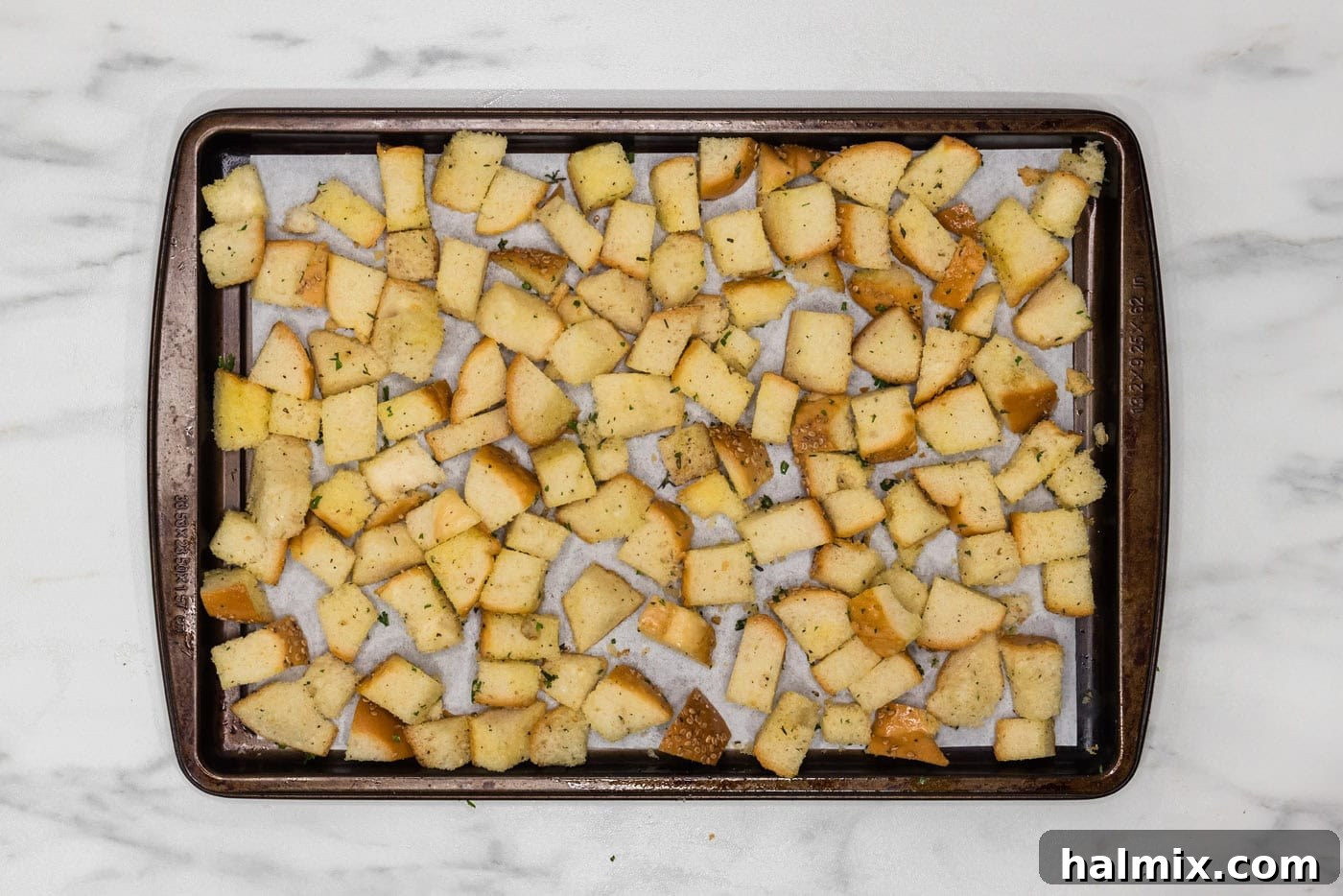 seasoned cubed bread on a baking sheet