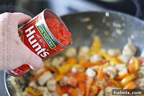 A can of Hunt's diced tomatoes and chicken broth are poured into the skillet.