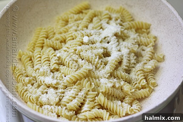 A close-up of a bowl filled with freshly cooked Rotini pasta, lightly dusted with Parmesan cheese.