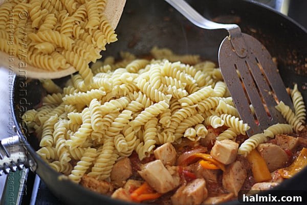 The Parmesan-coated pasta is added to the skillet with the chicken and pepper sauce and stirred together.