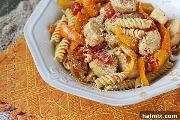 A beautifully presented bowl of Chicken with Peppers and Pasta, generously topped with Parmesan cheese, ready to be enjoyed.