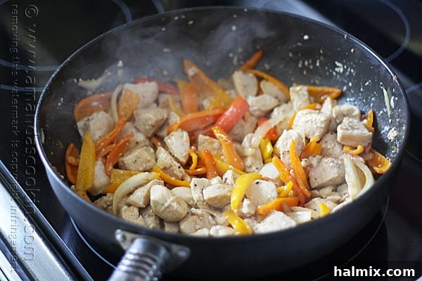 The browned chicken and sautéed vegetables are combined in the skillet and stirred.