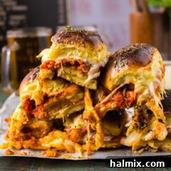 Close up photo of a stack of Chicken Parmesan Sliders, showing melted cheese and golden buns
