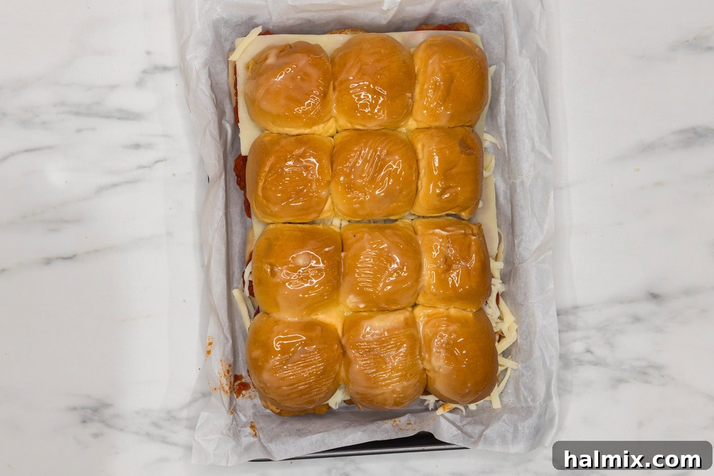 chicken parmesan sliders topped with melted butter in a baking dish