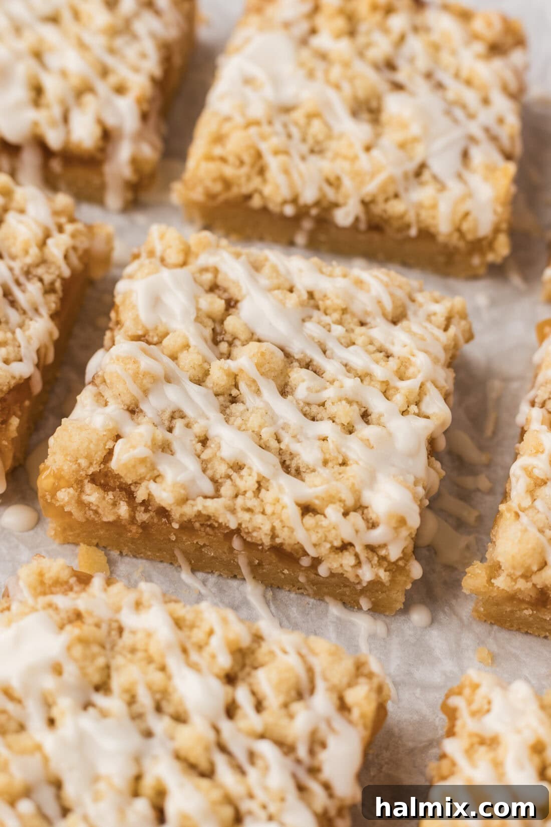 Close up photo of Lemon Streusel Squares on parchment paper, showing the crumbly topping and glaze