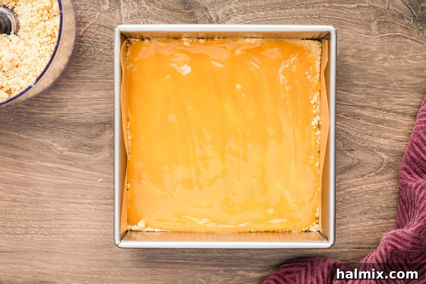 Lemon curd being spread evenly over the shortbread crust
