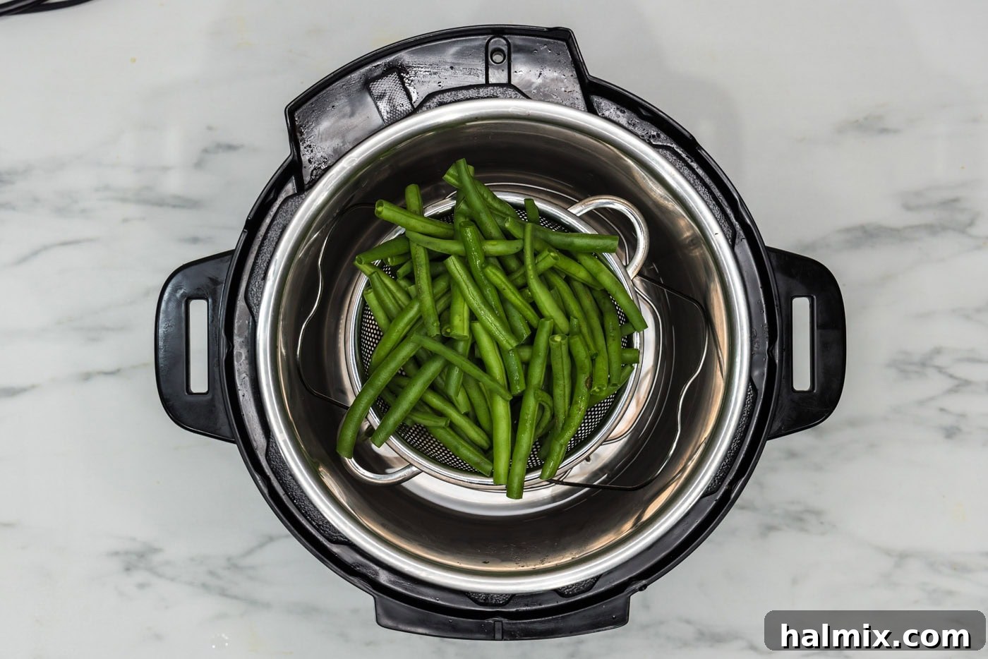 Fresh green beans neatly arranged in a steaming basket inside the Instant Pot.