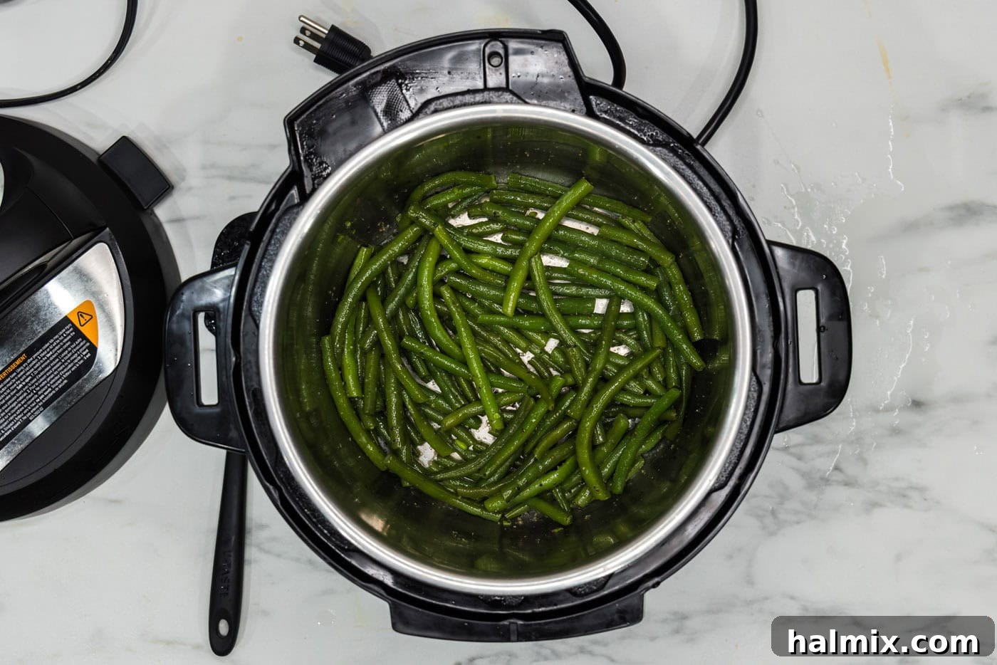 Cooked green beans tossed with melted butter and seasonings in the Instant Pot.