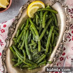 Instant Pot Green Beans in a metal platter topped with parmesan, a close-up shot of the perfectly cooked and seasoned vegetables.
