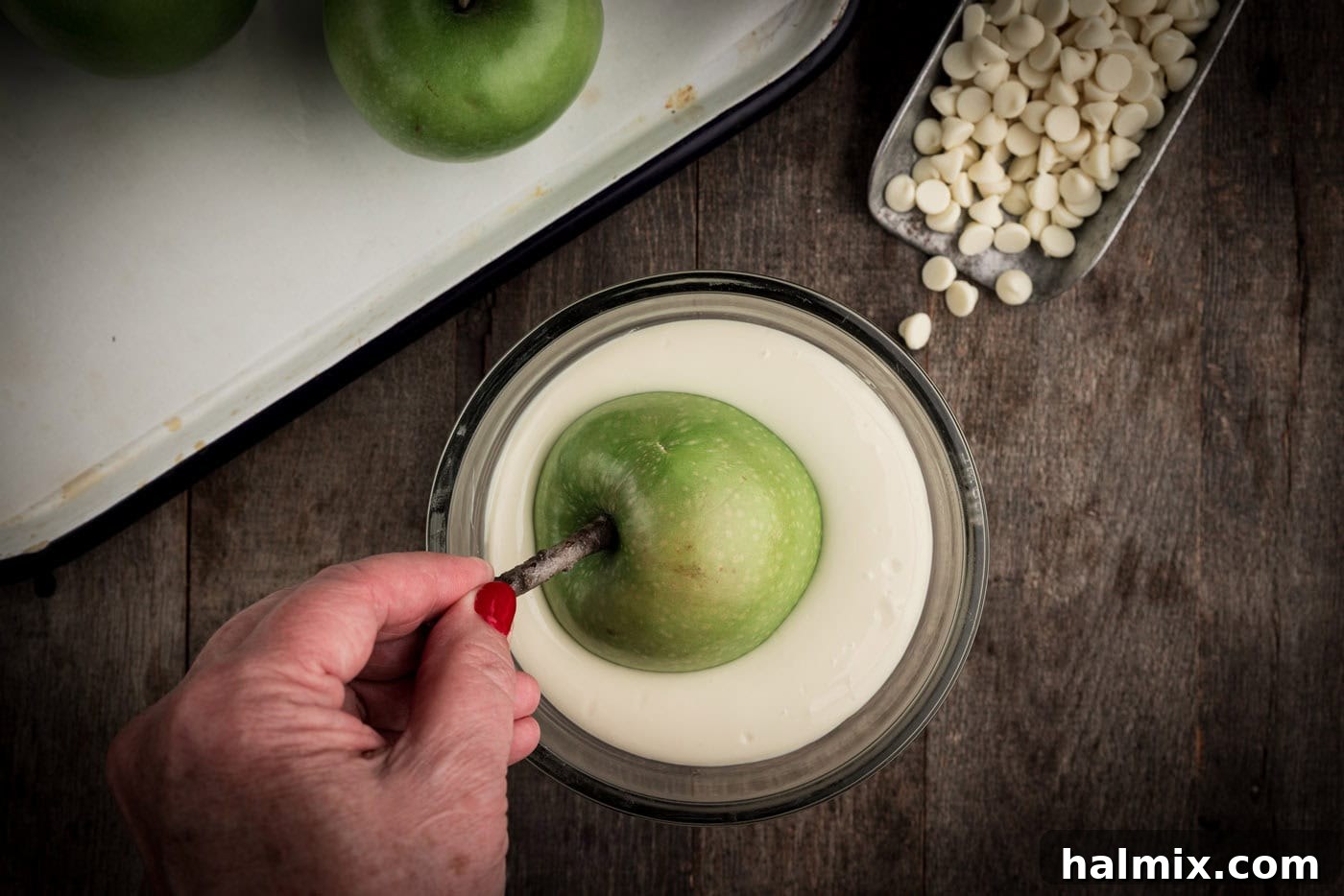 dipping skewered apple into melted white chocolate