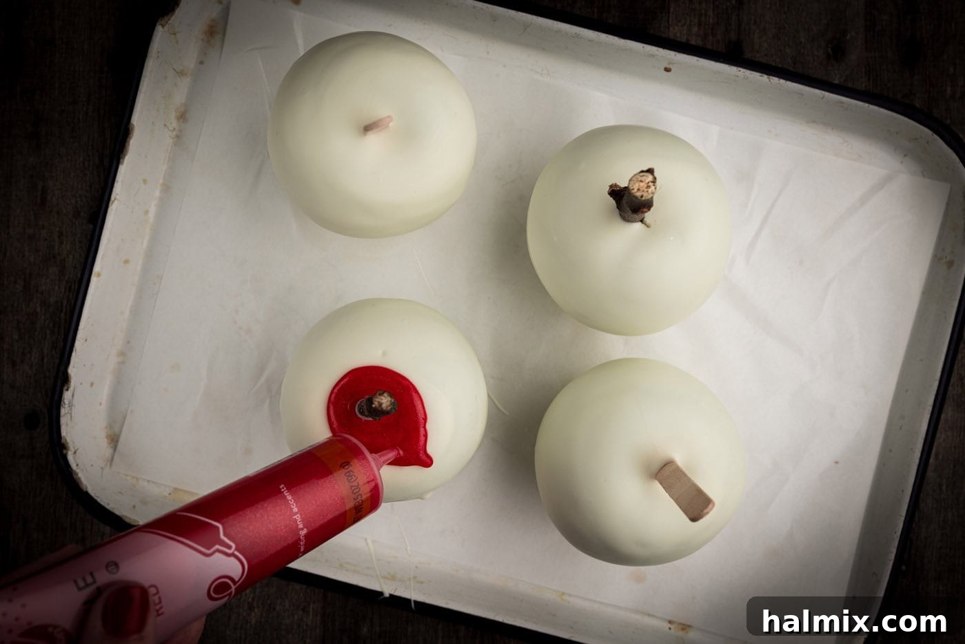 drizzling red gel over white chocolate candy apples