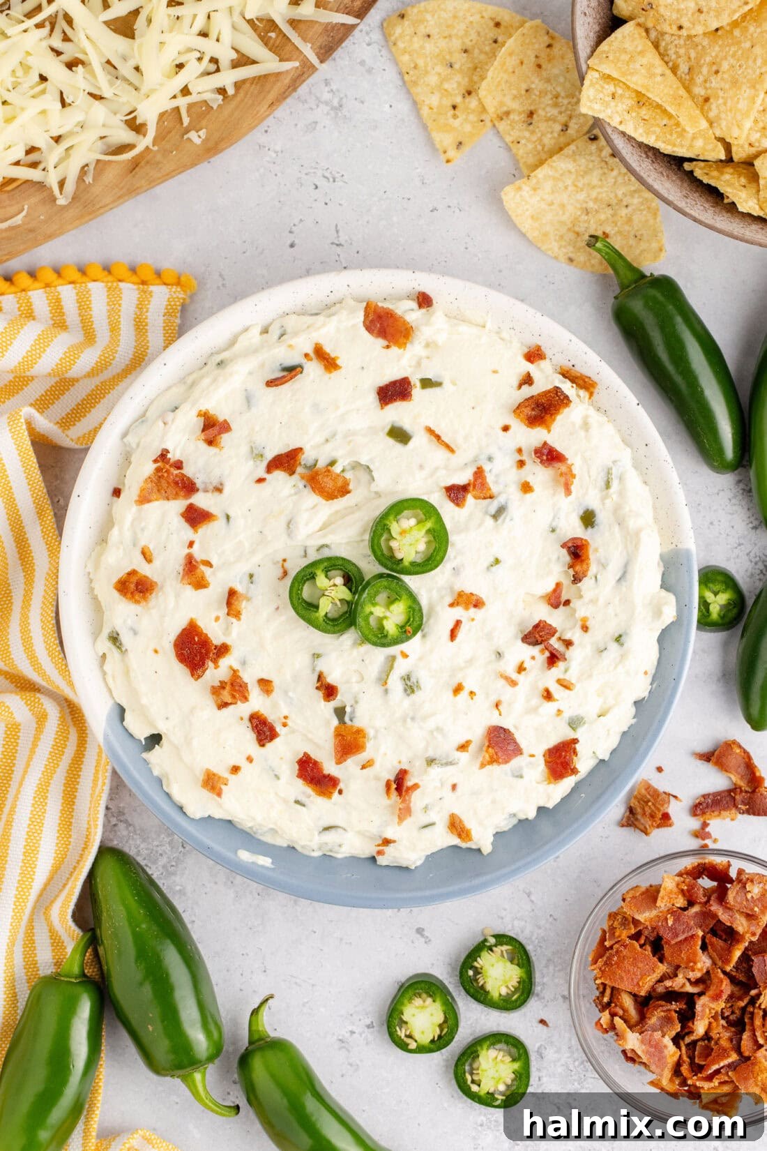 Bowl of Crockpot Jalapeno Popper Dip topped with crispy bacon pieces and fresh sliced jalapeno