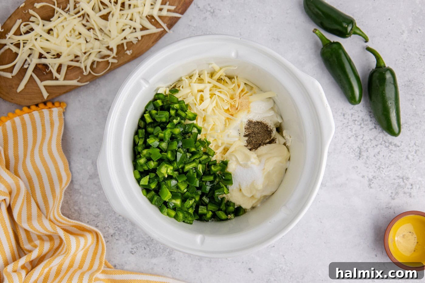 chopped jalapenos, mayo, sour cream, shredded cheese, and cream cheese in a slow cooker crock before cooking