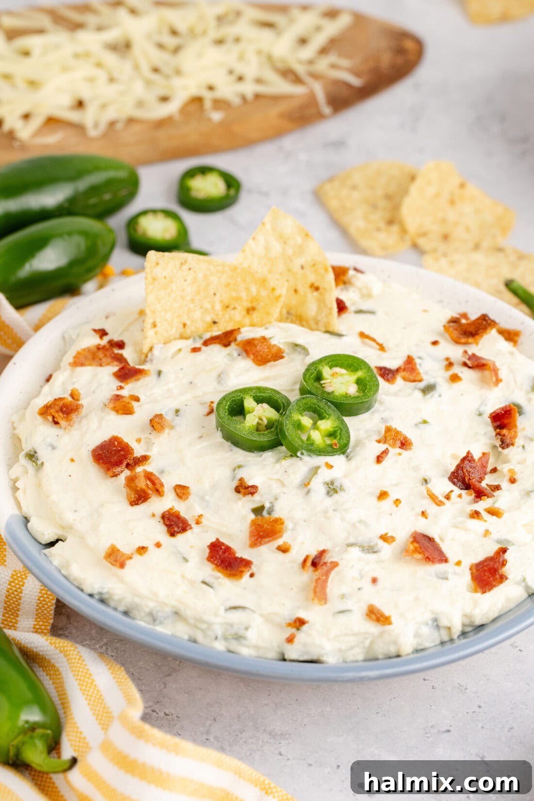 Close up photo of a bowl of Crockpot Jalapeno Popper Dip with two chips scooping into it, showing melted cheese