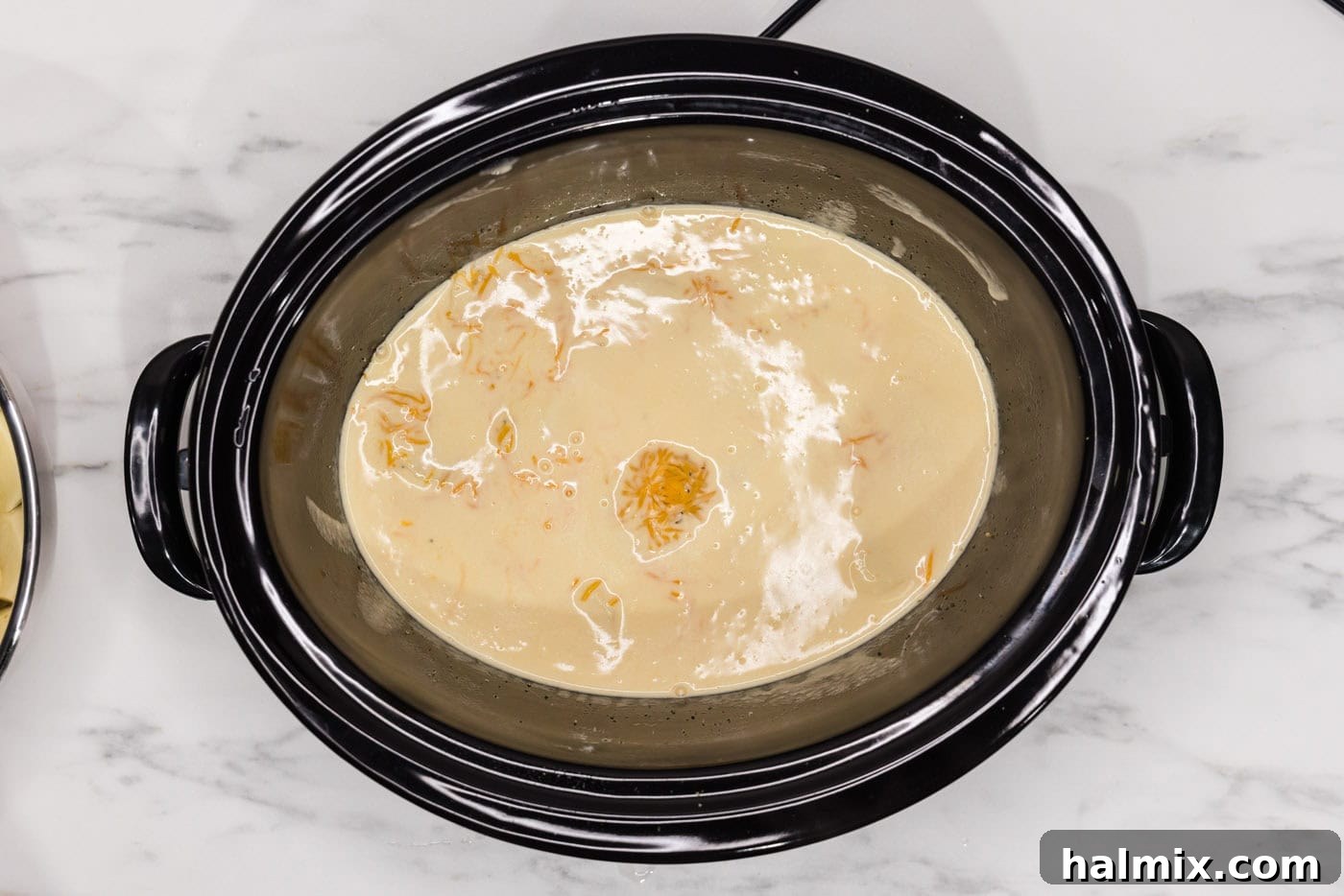 Rich and Creamy Slow Cooker Scalloped Potatoes 12 cheese sauce on top of sliced potatoes in a crockpot