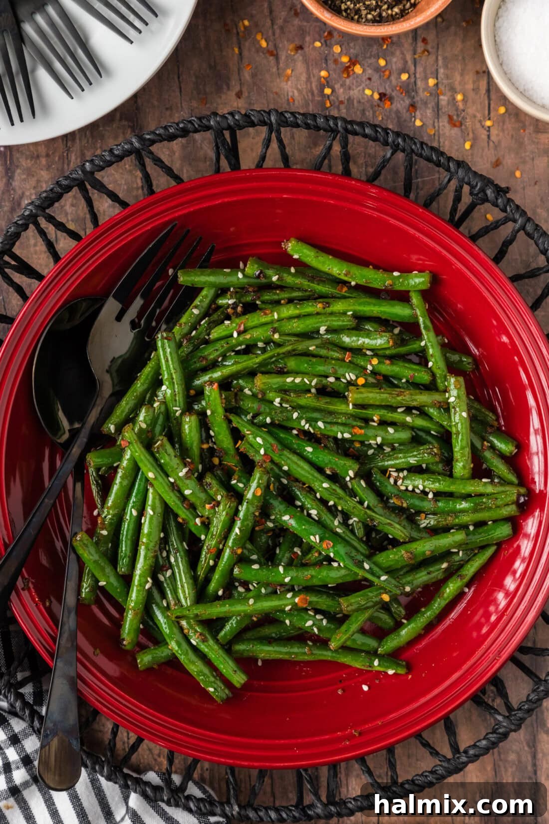 Sautéed Green Beans with Garlic and Lemon Zest 2 Sautéed Green Beans on a red plate with a serving fork and spoon resting to the side, ready to be enjoyed.