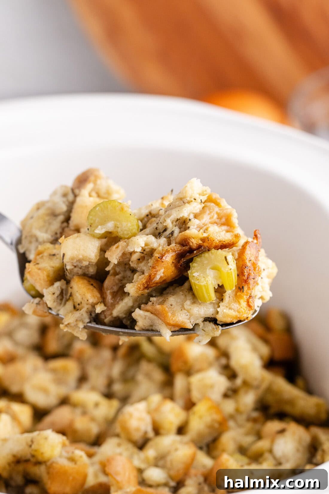 Close up photo of a spoonful of Crockpot Stuffing, showcasing its golden-brown top and tender interior.