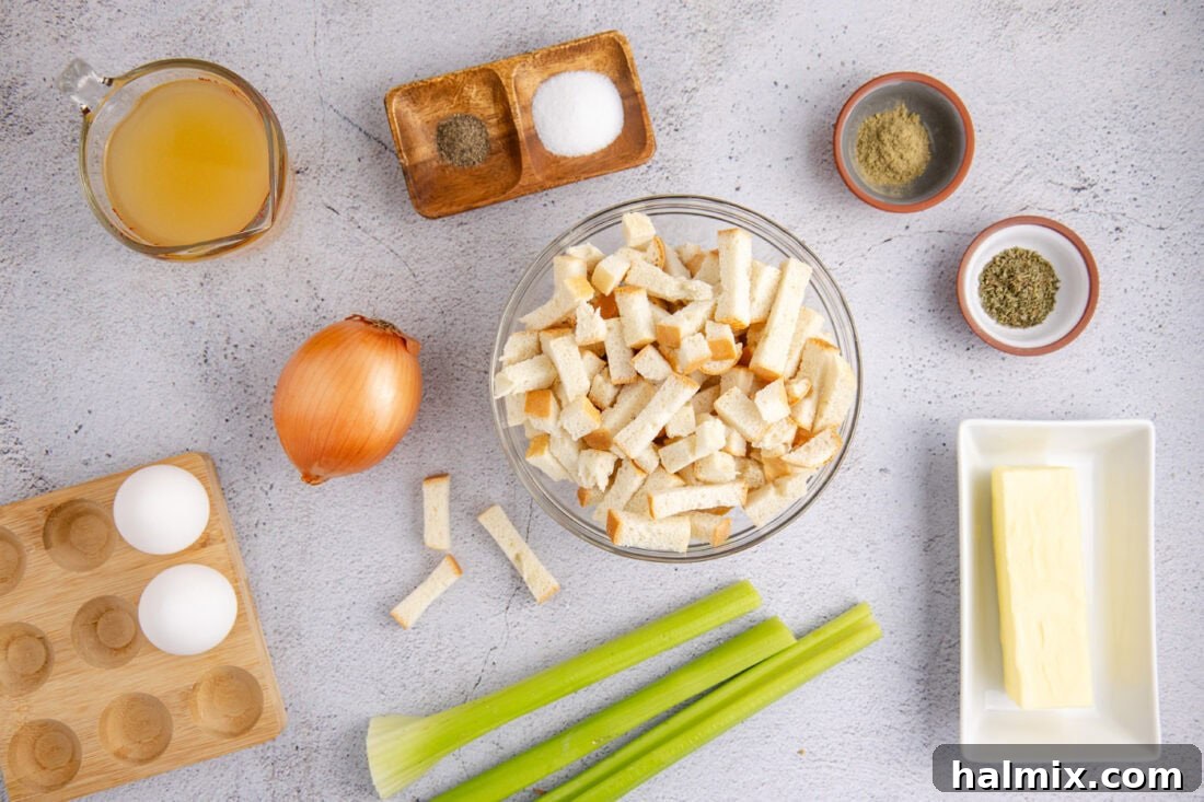 A flat lay photo showing all fresh ingredients for Crockpot Stuffing, including bread cubes, celery, onions, herbs, and butter.