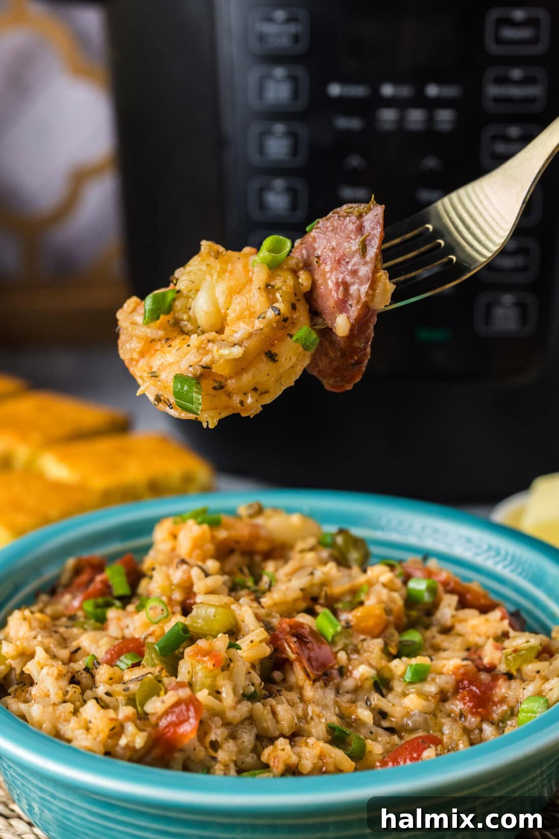 Effortless Instant Pot Jambalaya 2 Piece of shrimp and sausage on a fork held above a bowl of Instant Pot Jambalaya