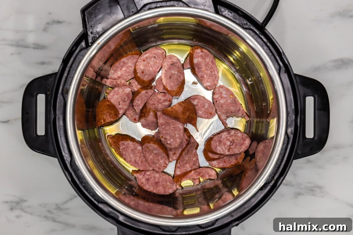 andouille sausage cooking with olive oil in a pressure cooker