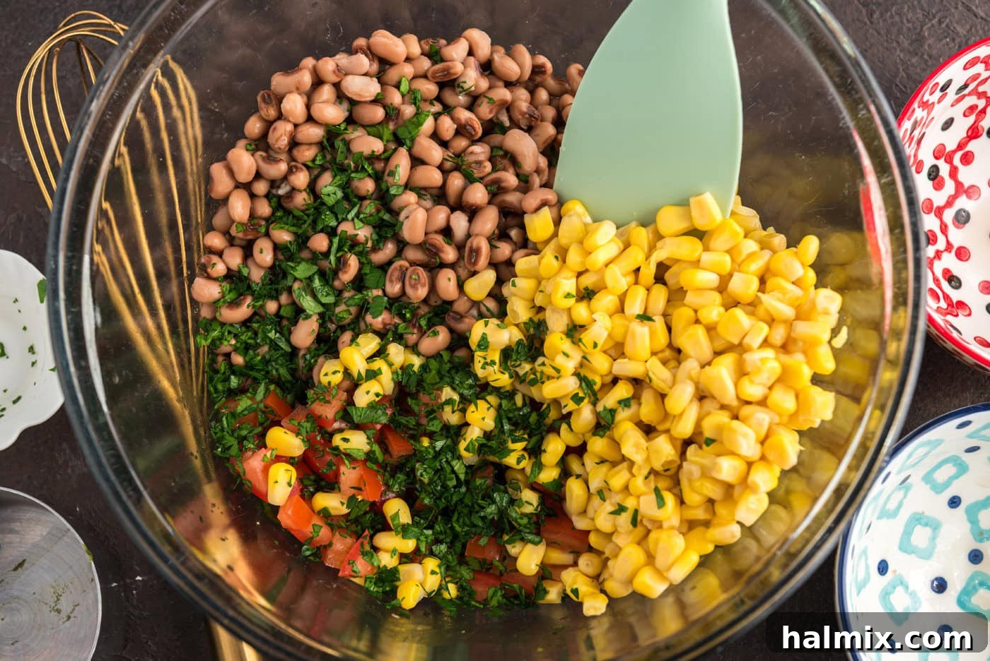 Prairie Jewel Dip 7 Step-by-step image showing all the Cowboy Caviar ingredients being stirred together in a large mixing bowl until thoroughly combined.