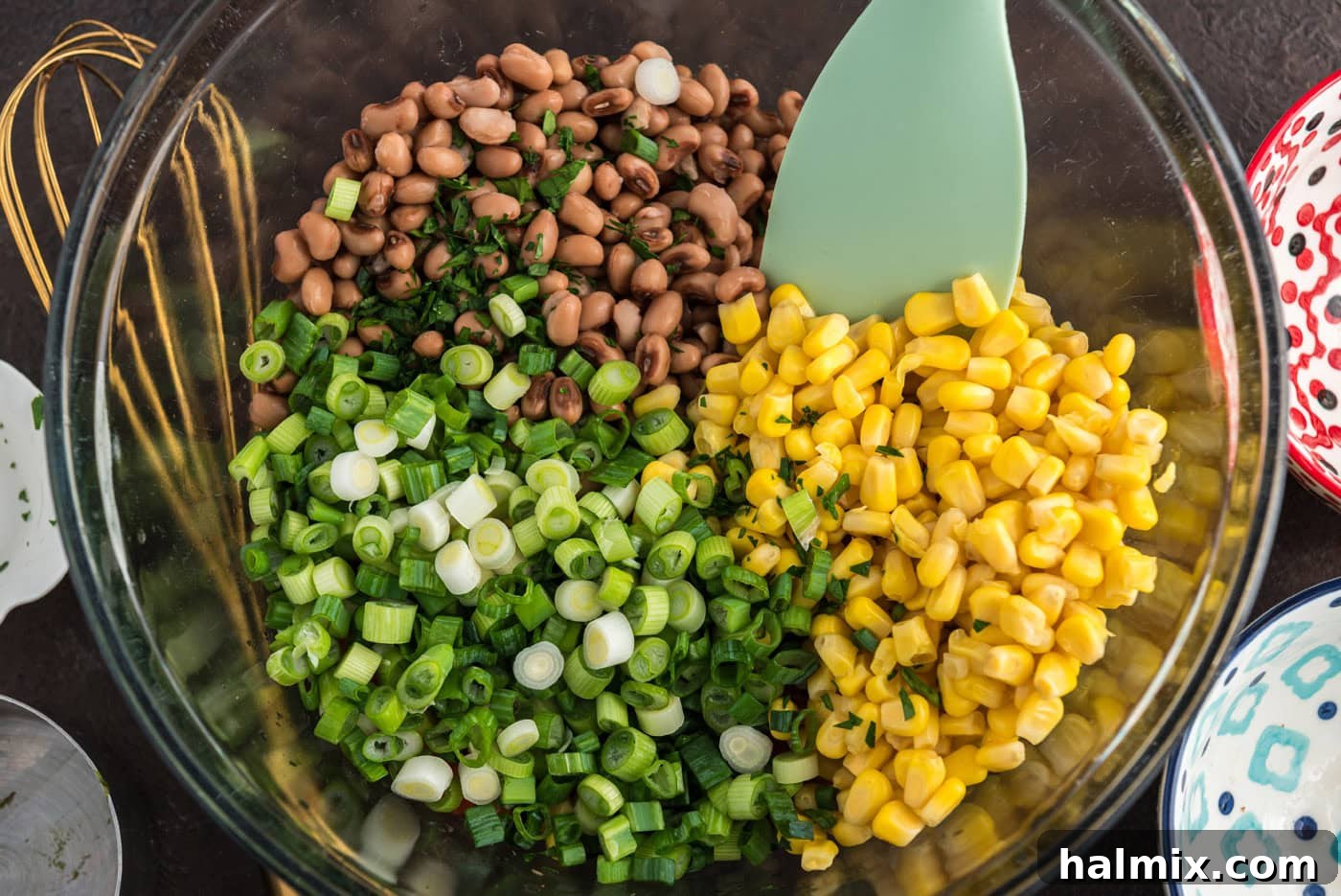 Prairie Jewel Dip 8 Step-by-step image capturing the moment green onions are added to the colorful bowl of mixed Cowboy Caviar ingredients.