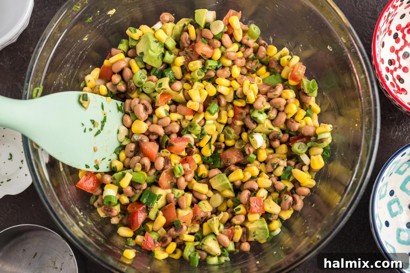 Prairie Jewel Dip 9 A beautifully mixed bowl of homemade Cowboy Caviar with a rubber spatula, showcasing the vibrant colors and fresh textures of the dip.
