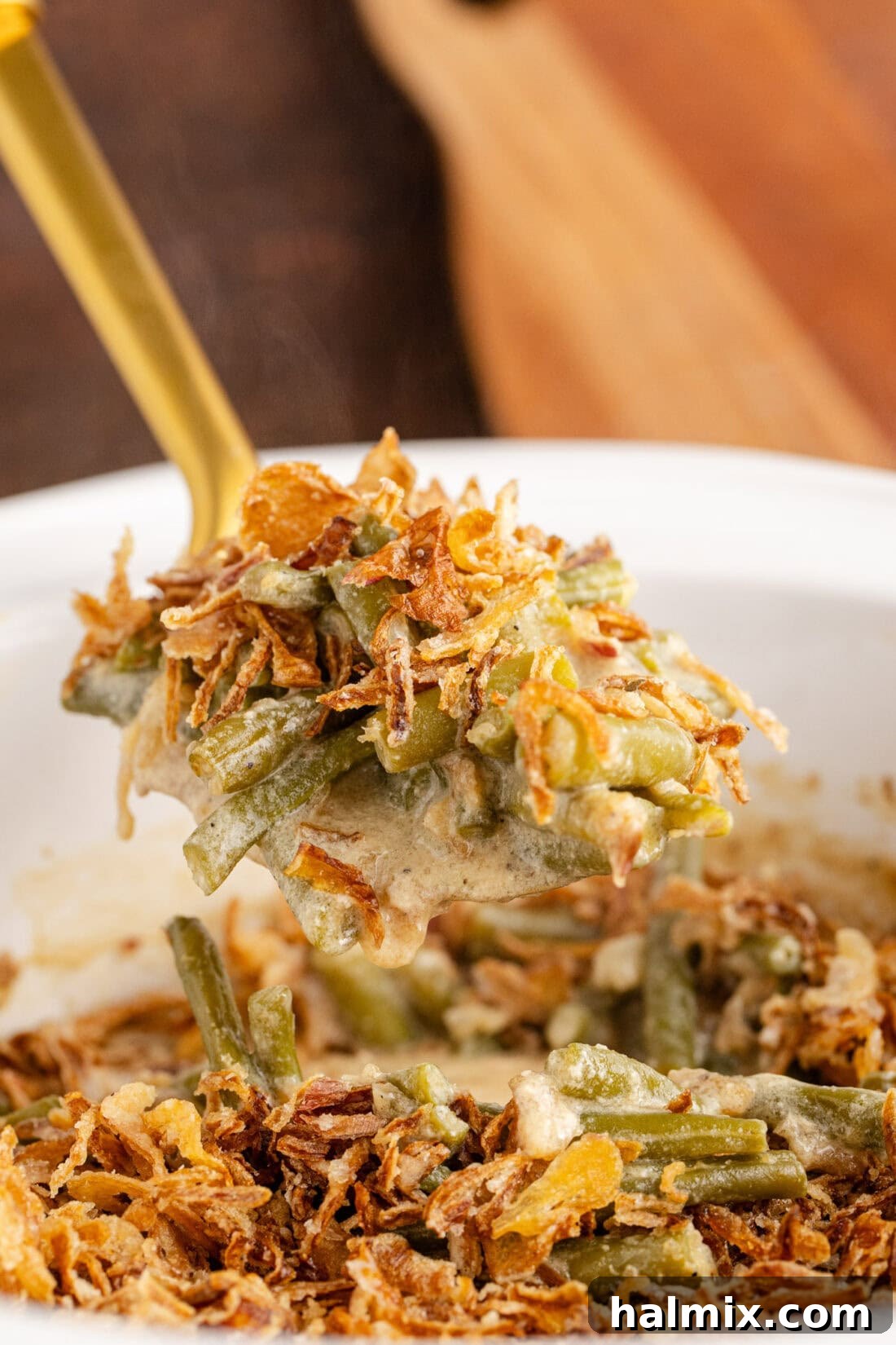 Close up photo of a spoonful of Crockpot Green Bean Casserole, showcasing its creamy texture and crispy onion topping.