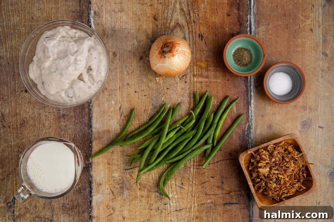 A flat lay photograph displaying all the ingredients required for Crockpot Green Bean Casserole, including fresh beans, cream of mushroom soup, and fried onions.