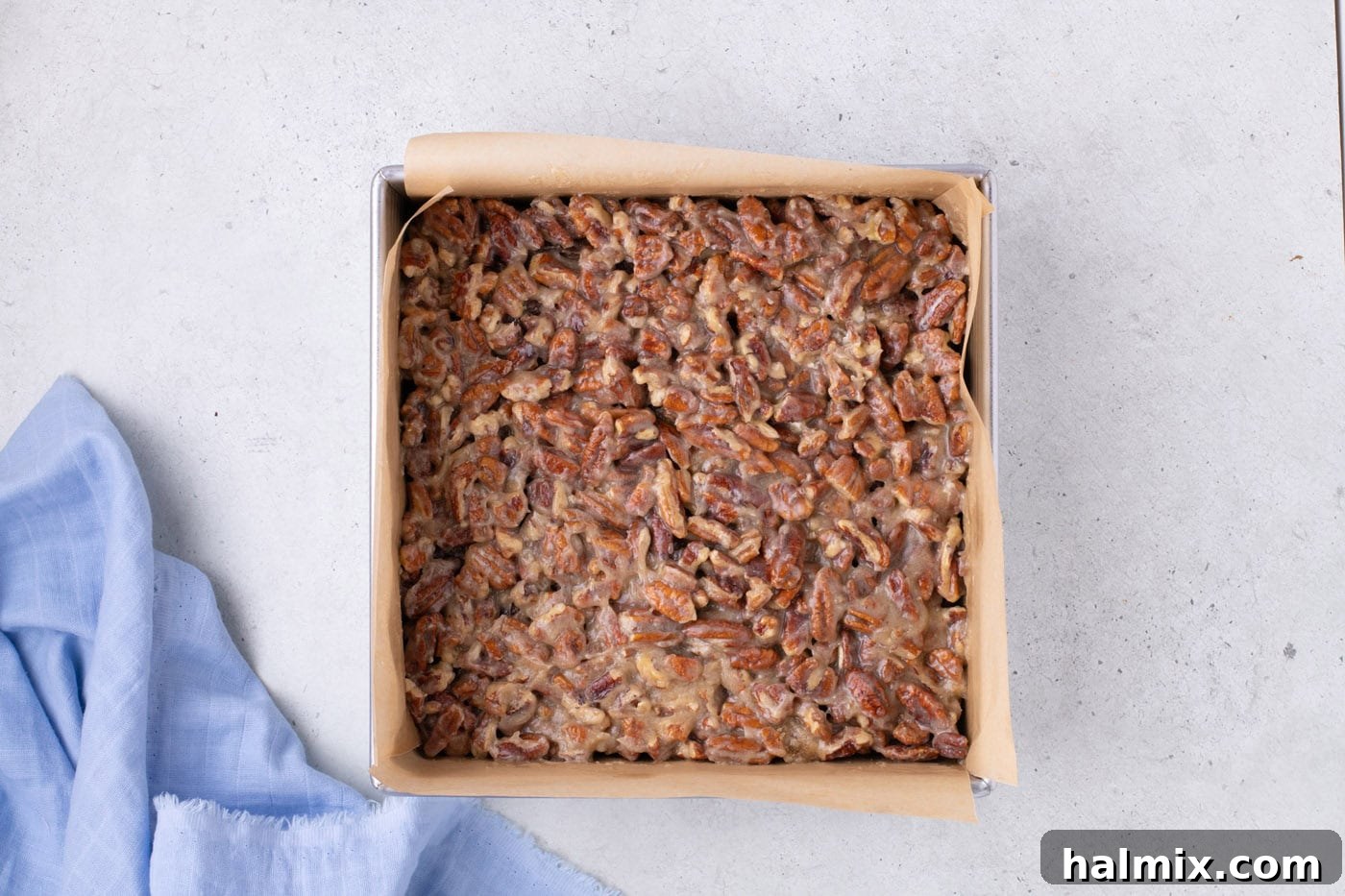 pecan pie topping on top of brownies in a baking pan