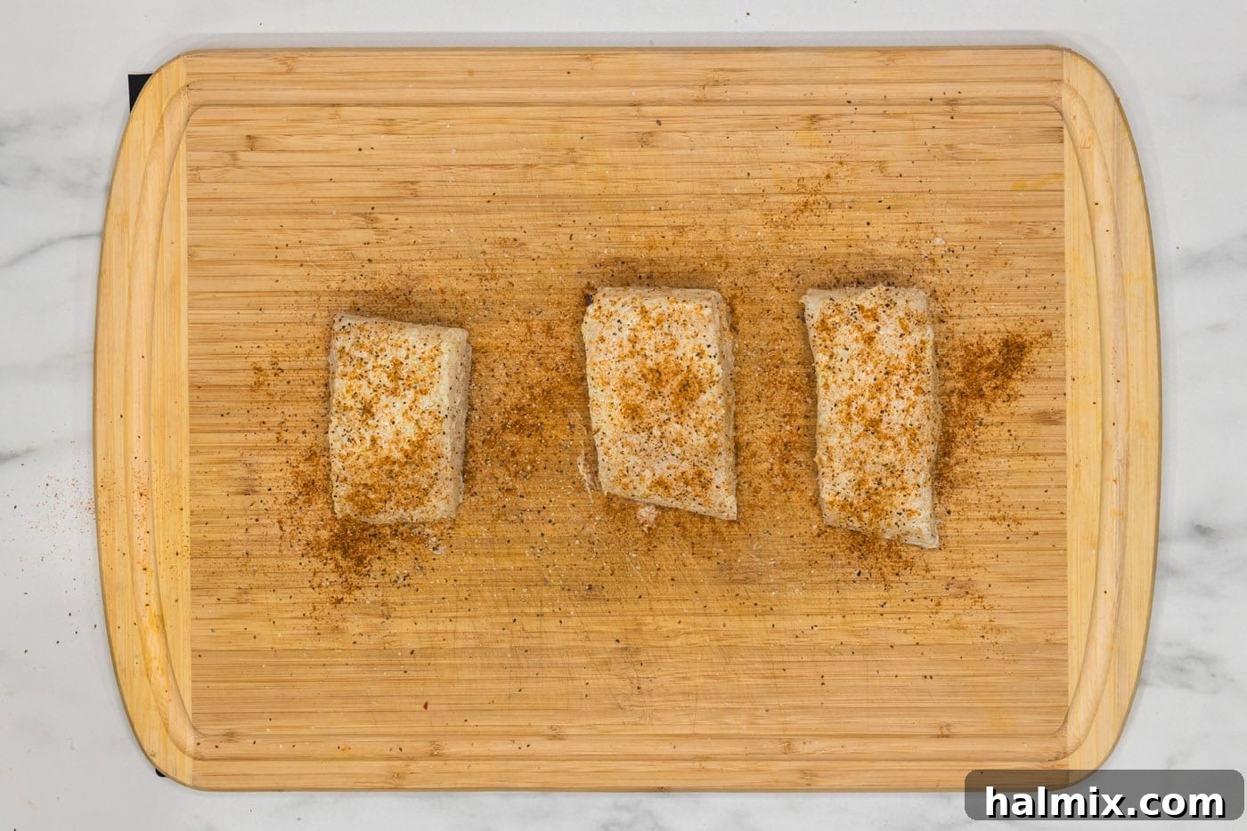 Golden Pan-Seared Chilean Sea Bass 7 seasoned chilean sea bass filets on a cutting board, perfectly coated