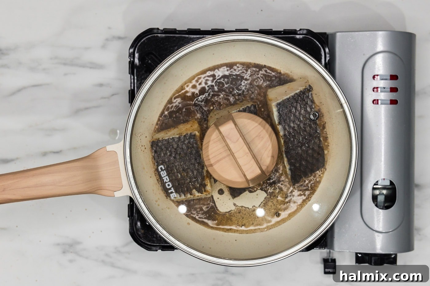 Golden Pan-Seared Chilean Sea Bass 9 lid on skillet over chilean sea bass, creating a moist cooking environment