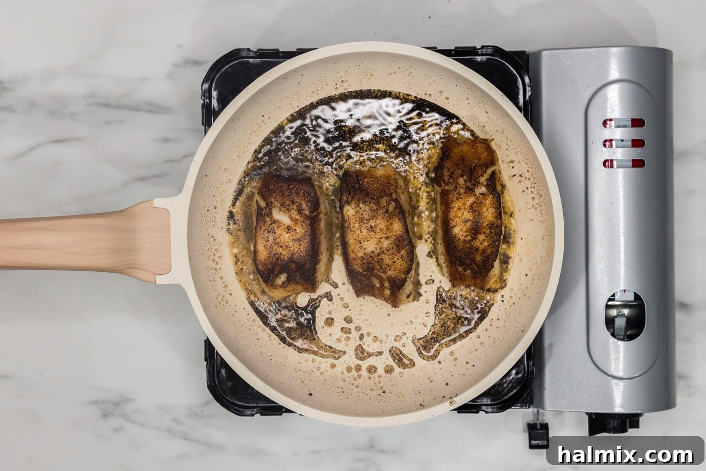 Golden Pan-Seared Chilean Sea Bass 10 pan seared Chilean sea bass cooking in a skillet, now flipped to sear the other side