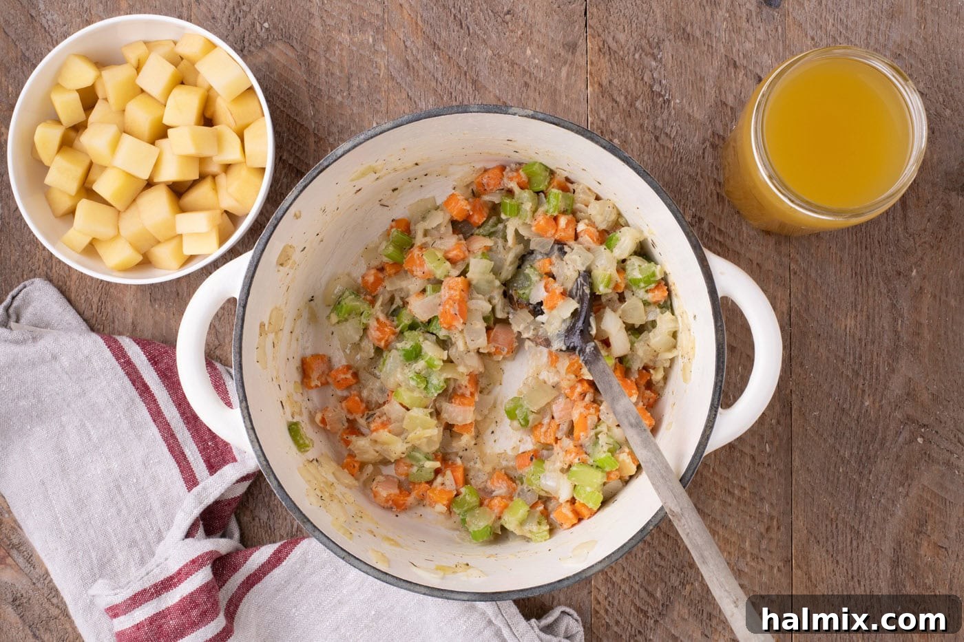 Flour being mixed into the sautéed vegetables in a Dutch oven, creating a rich, paste-like roux.