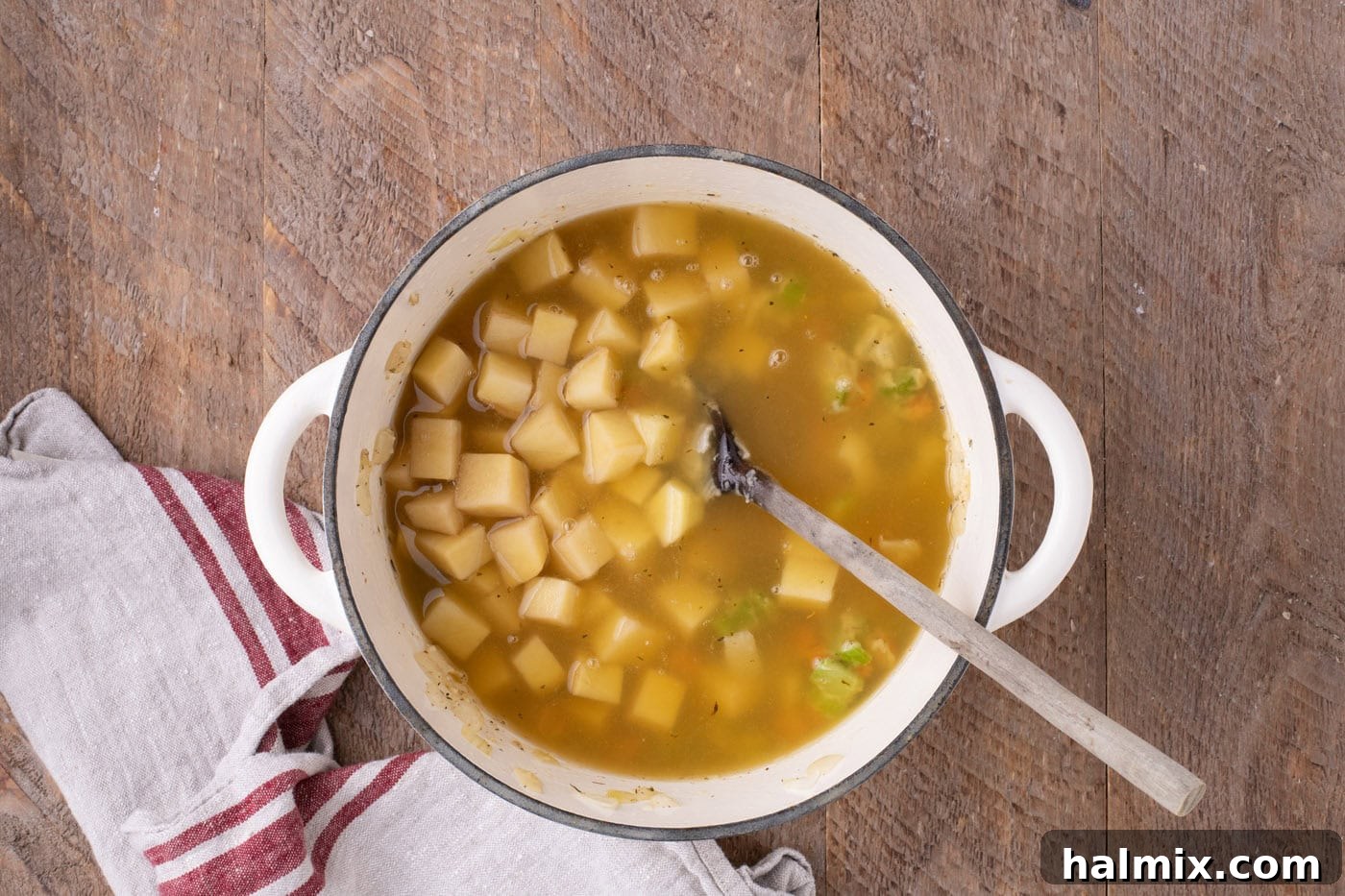 Diced potatoes and rich chicken broth added to the pot with the aromatic vegetables, ready to simmer.