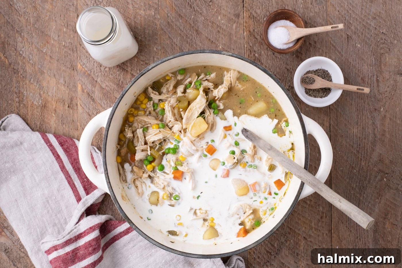 Heavy cream being gently stirred into the chicken pot pie soup, transforming it into a rich, creamy consistency.