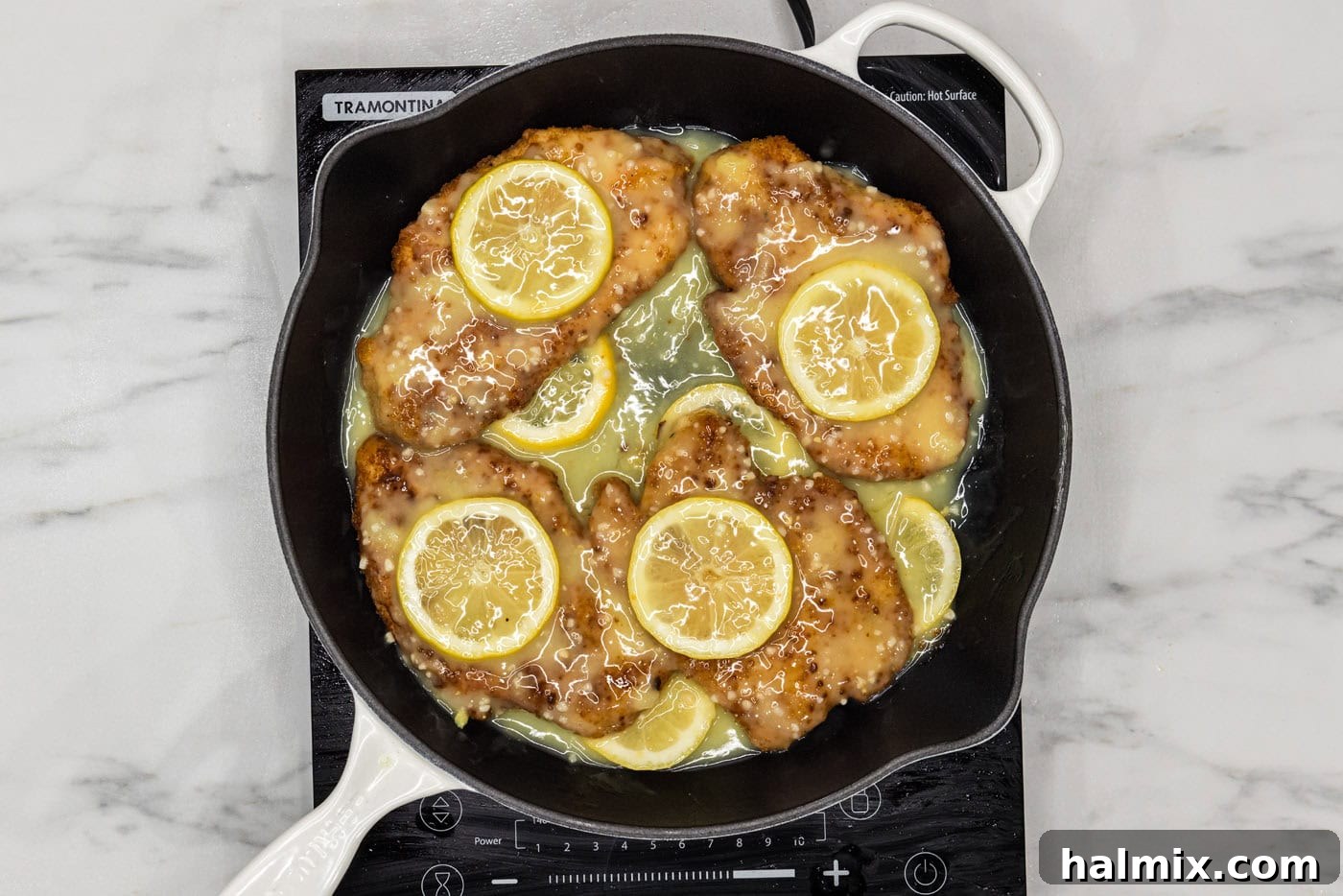 fried lemon chicken breasts in a pan of lemon garlic butter sauce