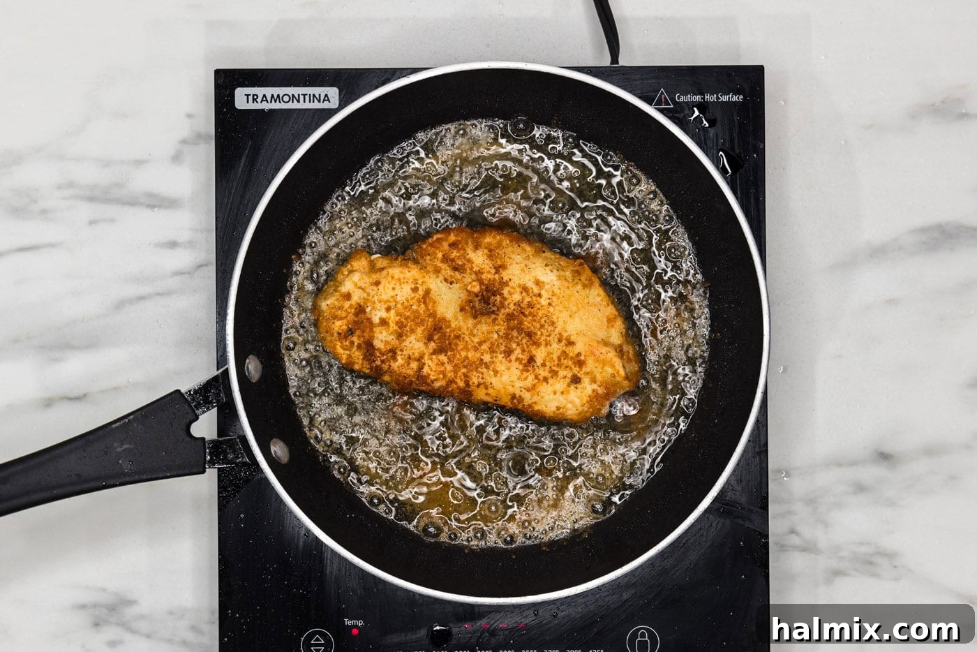 pan fried lemon chicken breast in a skillet of oil