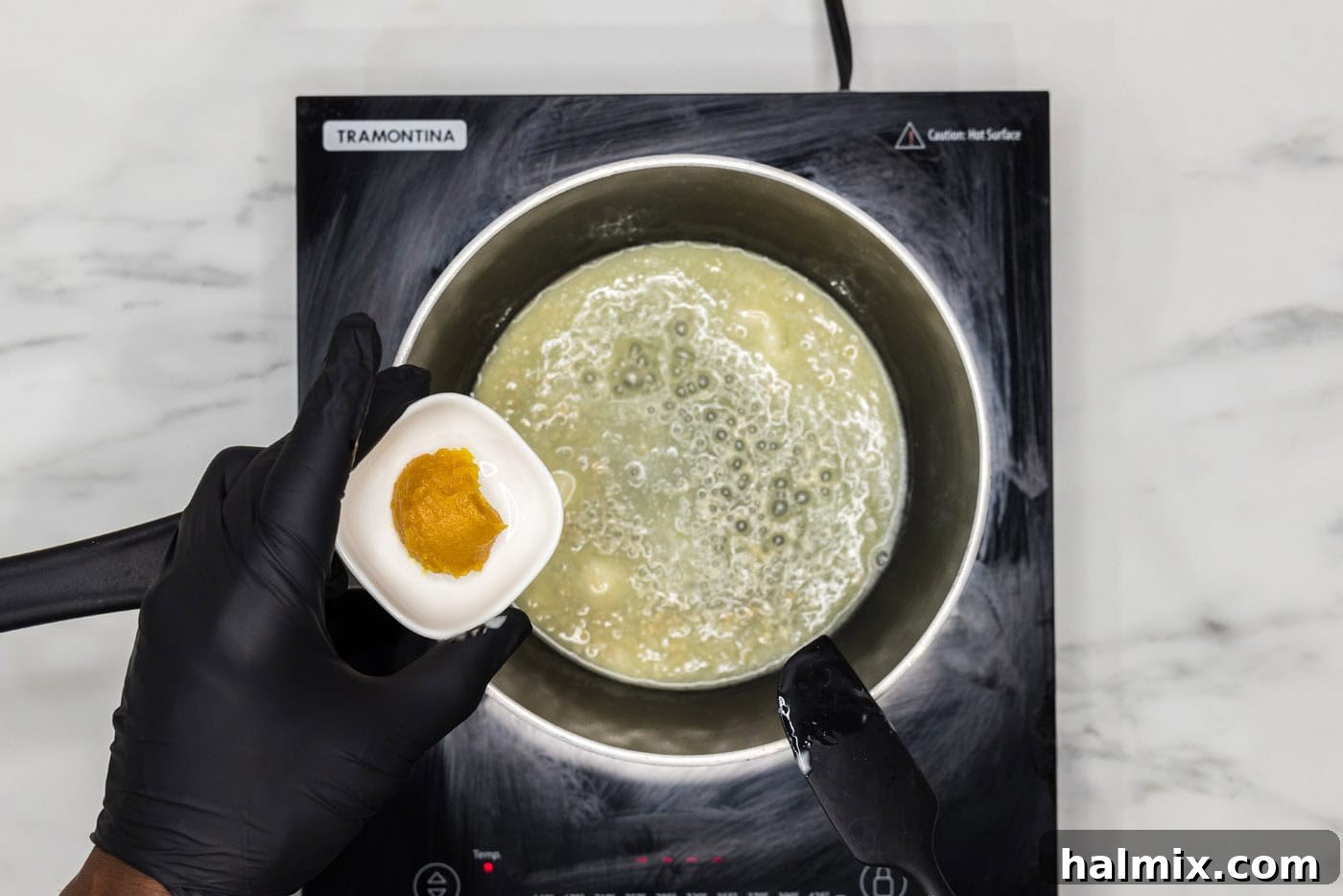 hand holding chicken base over melted butter in a saucepan