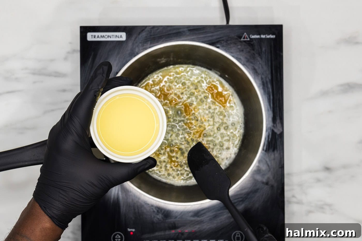 hand holding lemon juice over a saucepan of melted butter