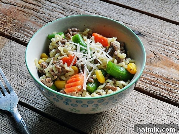 Flavorful Beef Ramen Skillet 3 A close-up photo of the finished ramen noodle and beef skillet in a blue and white bowl, showing tender noodles and browned beef.