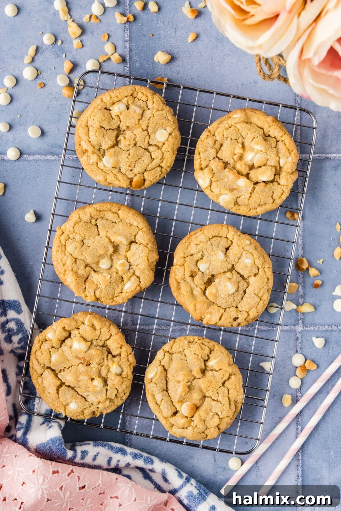 A cluster of freshly baked White Chocolate Macadamia Nut Cookies resting on a wire cooling rack, emitting warmth and delicious aroma.