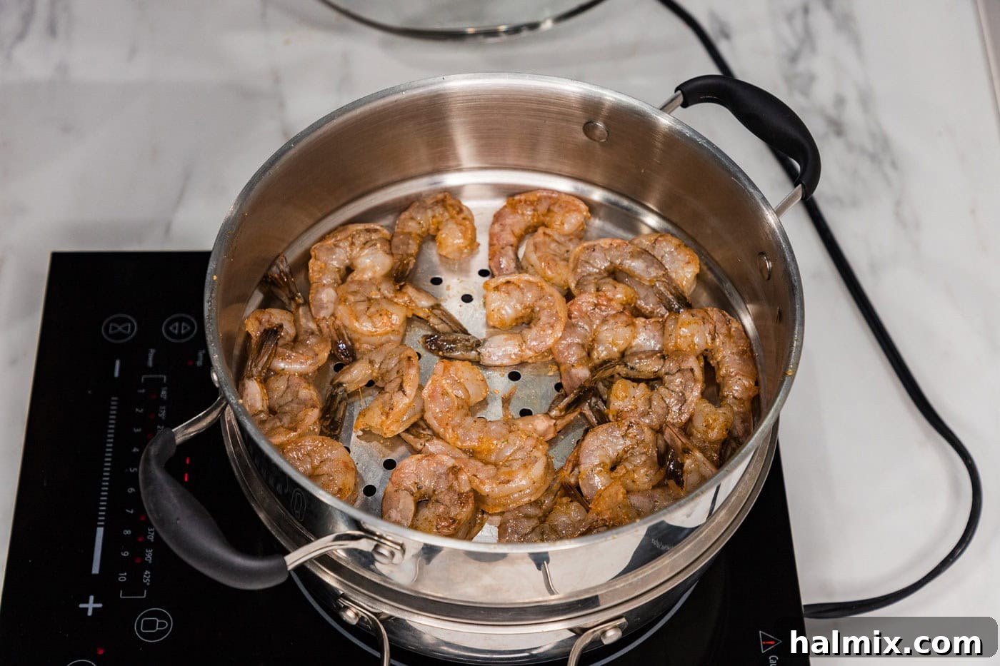 Seasoned shrimp placed neatly in a steamer pot basket, ready for cooking.
