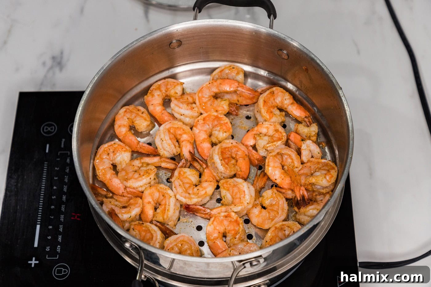 Cooked steamed shrimp, vibrant pink and perfectly curled, resting in the steamer basket.